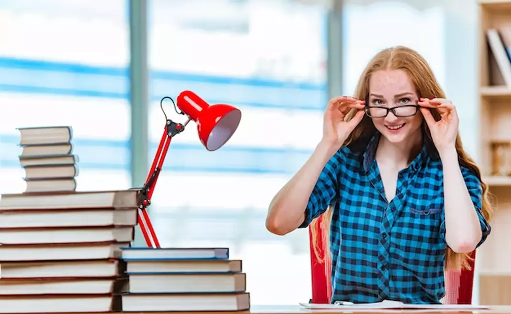 donna con occhiali alla scrivania piena di libri